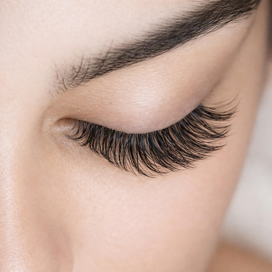 Comparison photo showing four styles of eyelash extensions: Classic, Hybrid, Volume, and Mega Volume on different clients’ eyes.